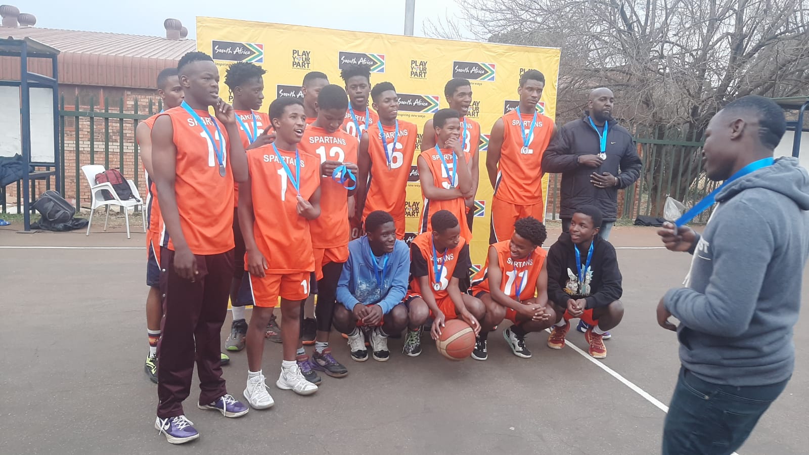A team in orange jerseys gathers together wearing medals